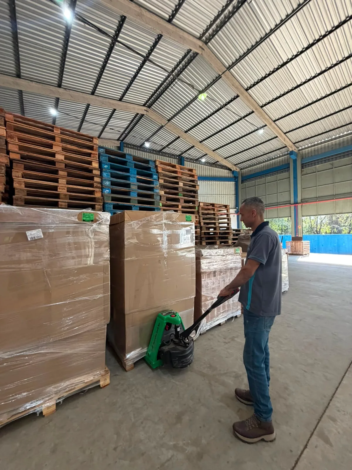 Profissional movimentando mercadorias paletizadas com transpaleteira